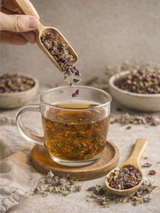 Loose leaf organic echinacea being poured from a wooden spoon into a glass mug, showing the high-quality cut of the dried botanicals.