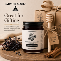 A jar of Farmer Soul Elderberry Cinnamon Raw Clover Honey is styled on a wooden board with cinnamon sticks, elderberries, a wooden honey dipper, and a kraft gift box with a burlap ribbon. Text on the left reads 'Great for Gifting'.